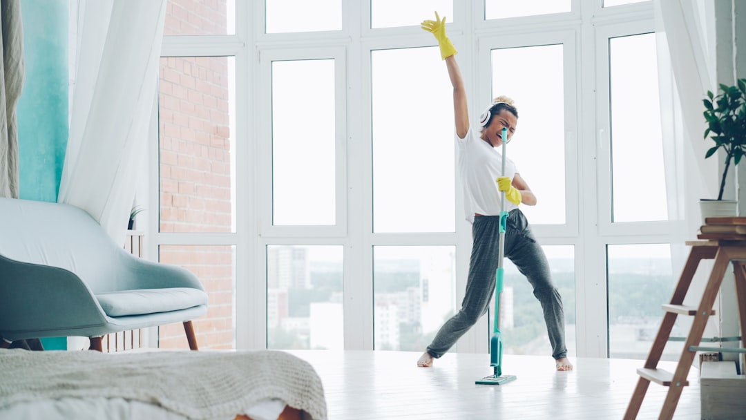 our-story Joyful young woman is enjoying music in headphones, dancing and singing during routine cleanup at home, girl is mopping floor and having fun. People, technology and houses concept.