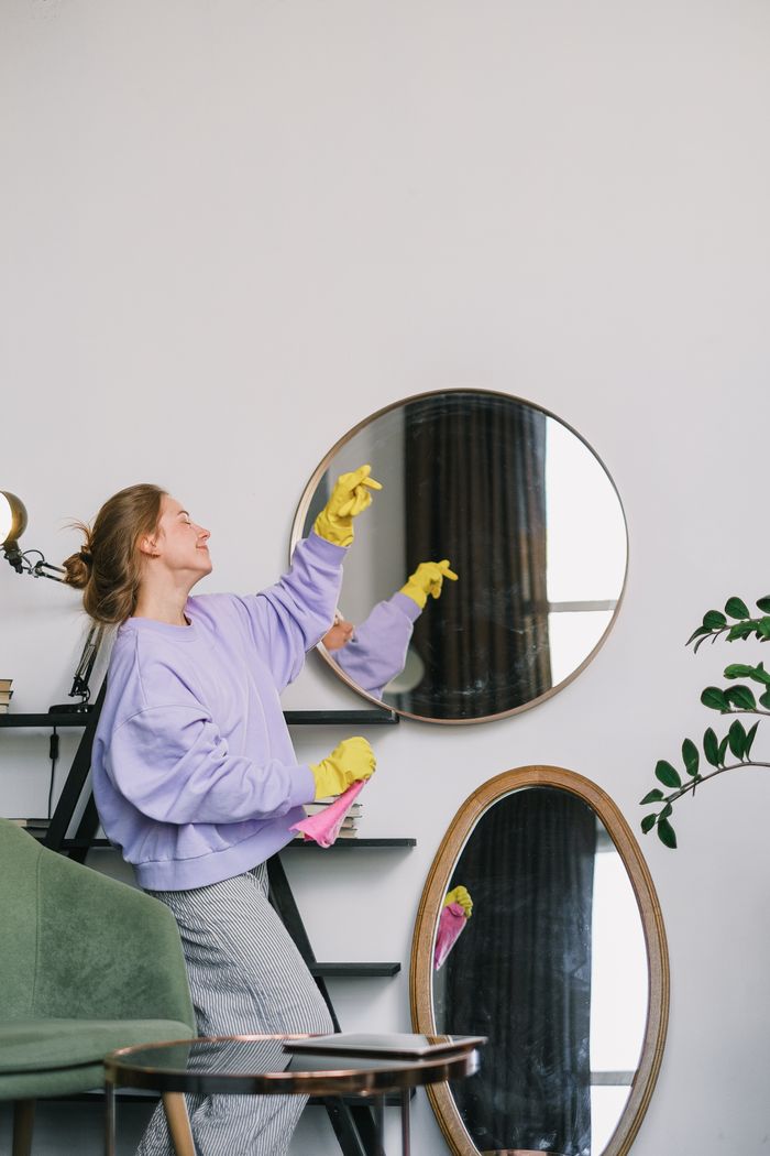 gallery-04 Side view of cheerful young female in casual clothes and yellow latex gloves standing near mirrors and dancing while cleaning apartment in daytime
